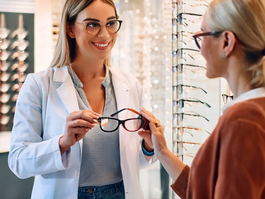 Firefly An optometrist assisting a customer with frame selection in a well-lit, modern eyewear store